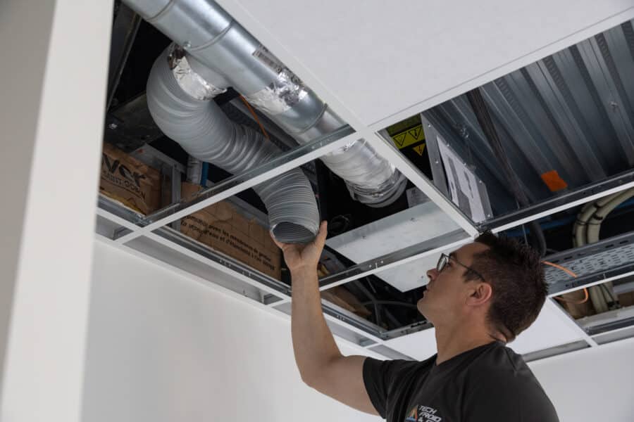 Technicien inspectant conduits de ventilation au plafond