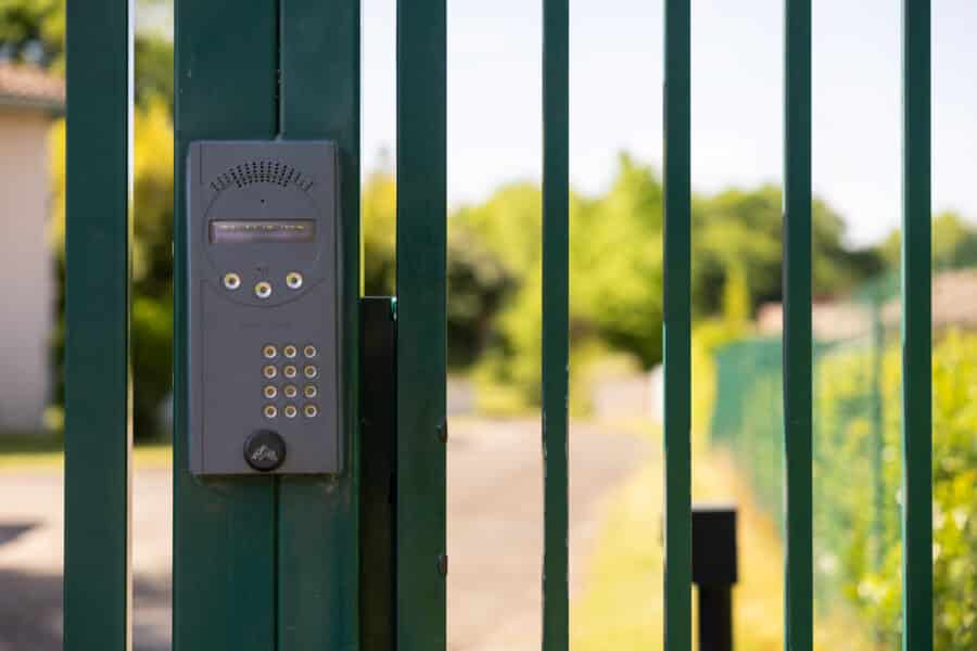 Clavier d'interphone sur une grille métallique verte.