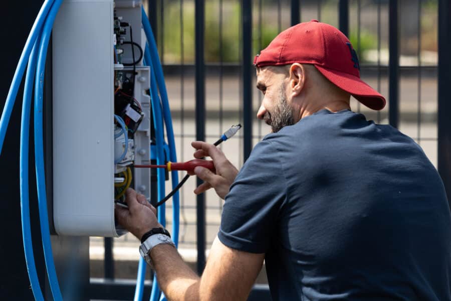 Technicien répare un boîtier électrique extérieur.