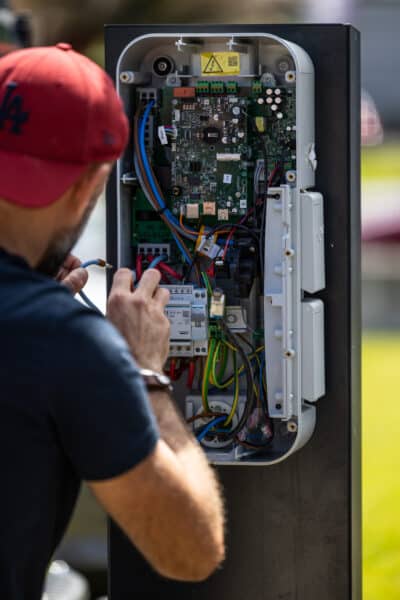 Technicien répare une borne de recharge électrique.
