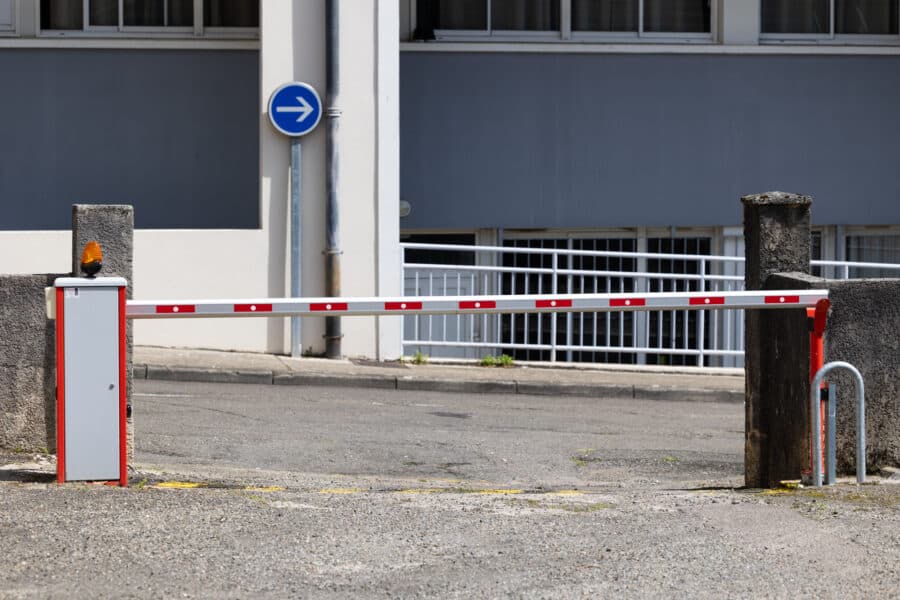 Barrière de sécurité fermée devant un bâtiment industriel.